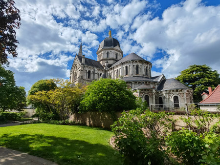 Cathedral with dome and spire surrounded by trees and garden under blue sky