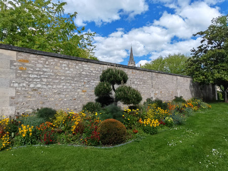 Flower garden along stone wall with church spire in the background