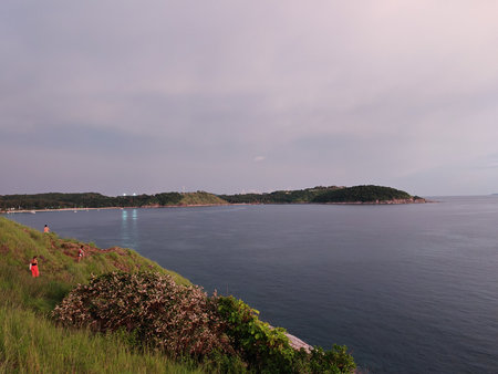 Coastal View with Green Hillside and Calm Sea at Sunsetの写真素材