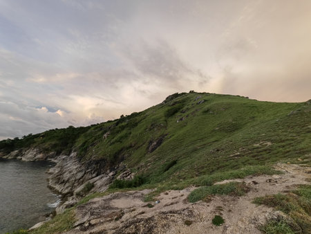 Rocky Green Hill by the Sea at Sunsetの写真素材
