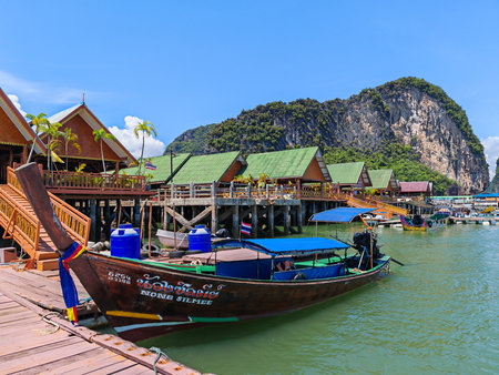 Traditional wooden boat at pier with houses on waterの写真素材