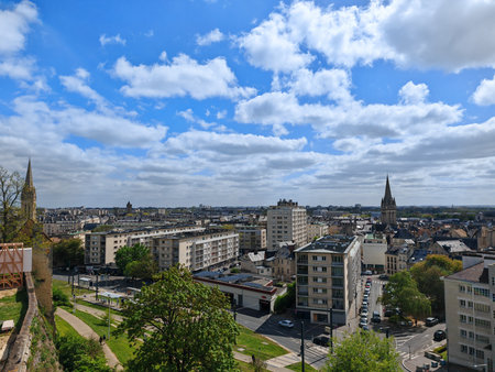 Cityscape with modern buildings and church spires under cloudy sky