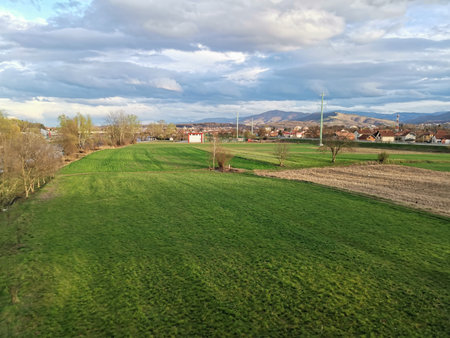 Green meadow landscape with distant hills and cloudy skyの写真素材