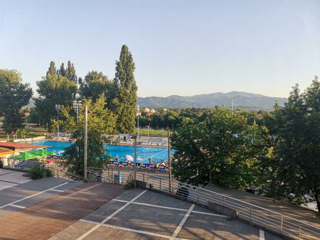 Outdoor swimming pool with trees and distant hills at sunset