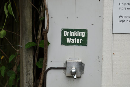 Drinking Water Signage Next To Faucet Surrounded By Greenery