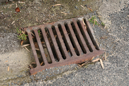 Rusty Street Drainage Grate Beside Weathered Pavementの写真素材