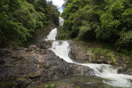 Tiered Mountain Waterfall Cascading Through Lush Forestの写真素材