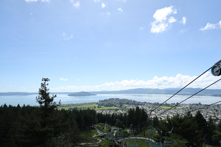 Chairlift Over Forested Hillside Lakeside Townの写真素材
