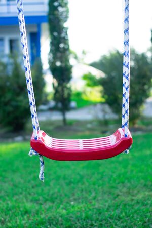 lonely empty children's swing on grass backgroundの写真素材