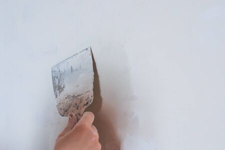 Plastering man hand with plaste and plaster spatula trowel in wallの写真素材