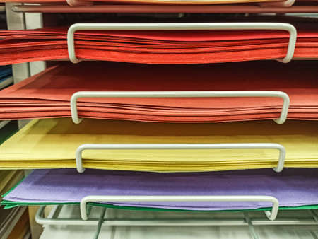 Sheets of colored cardboard for designer creative works. Stacks of colored drawing paper in the store. Colorful art papers on a shelf for sale in a stationery store.の写真素材