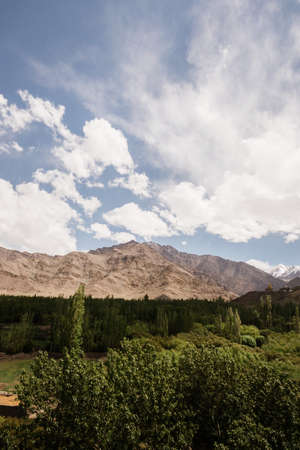 wide-angle arid and dry Himalayan mountain landscape with clouds and trees In Leh, Ladakh, Indiaの写真素材