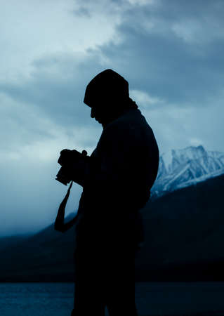 silhouette of a man with a camera in the cold mountainous region of Himalayas, Pangong Lake, Ladakh, India.の写真素材