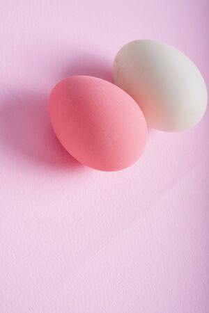 Pink egg and white egg over pink background. Vertical shot.の写真素材