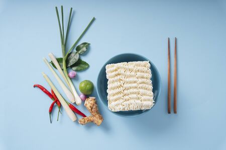 Top view - Instant noodle and chopstick with Tom Yum ingredients over blue background.の写真素材