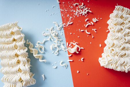 Crumble instant noodles over red and blue background.の写真素材