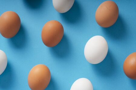 Top view - Brown and white eggs over blue background.