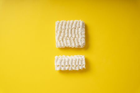 Crumble instant noodles over yellow background.