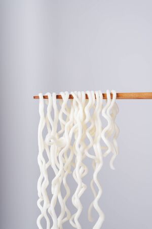 Sideview - eating instant noodle with wooden chopstick over white background.の写真素材