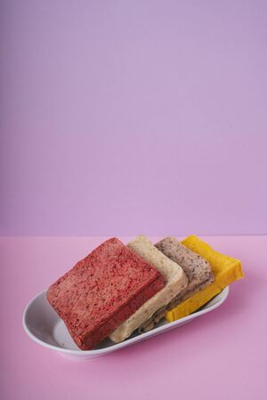 Four colourful Home made organic sliced bread on a plate in purple pink room.