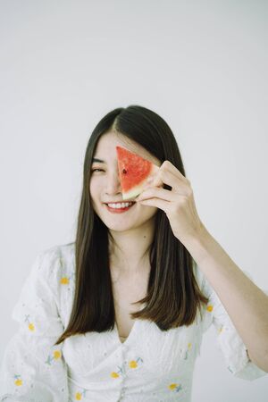 Beautiful asian young thai woman long dark hair with piece of watermelon. Isolate over white background.の写真素材