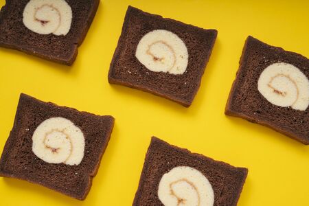 Dark chocolate roll sliced bread over yellow background.