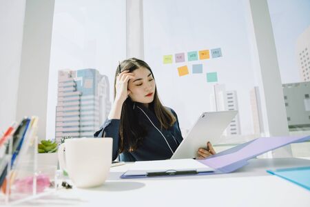 Serious working life in the office. Beautiful asian young thai businesswoman long dark hair having problem working too much. City background.の素材 [FY310149696118]