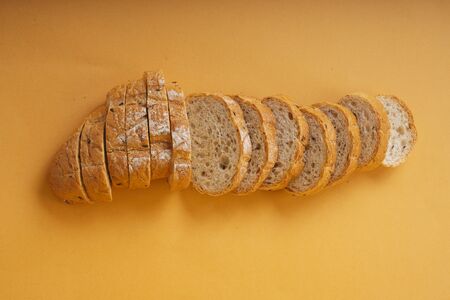 Top view - Sliced of loaf bread over orange background.