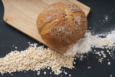Top view - Whole wheat loaf bread on wooden pad. Black background.
