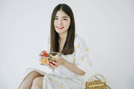 Beautiful asian young thai woman long dark hair with fruit in glass bowl. Picnic concept. Isolate white background.の写真素材