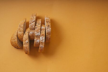 Top view - Sliced of loaf bread over orange background.