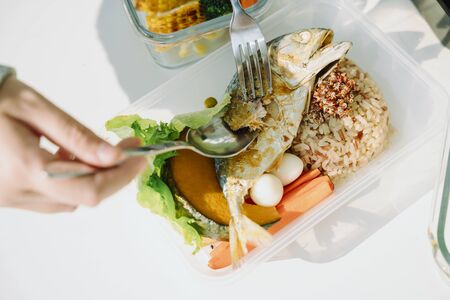 Top view of people eating deep fry mackerel and rice with healthy fresh vegetable. Food delivery....
