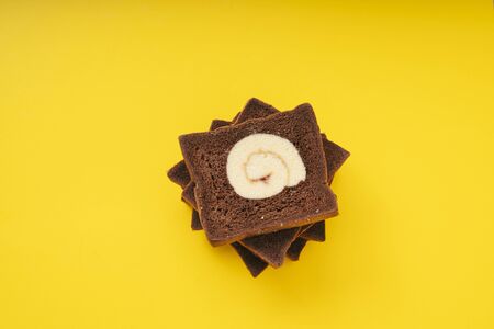 Stack of Home made organic dark chocolate roll sliced bread over yellow background.の写真素材