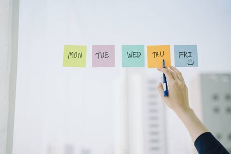Beautiful asian young thai woman long dark hair making schedule on sticky paper note on glass wall. Businesswoman arrange meeting.の写真素材