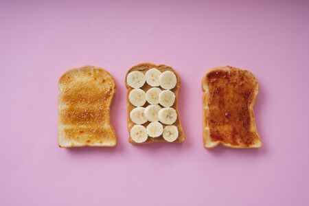Top view - Grilled sliced bread topping with banan and jam over pink background.の写真素材