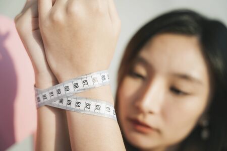 Fashion portrait - Beautiful asian thai woman tie her hands with measure tape.
