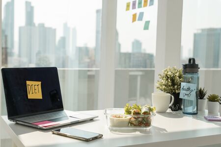 City background. Working office desk with laptop computer and fresh spring roll. Healthy diet food.の写真素材
