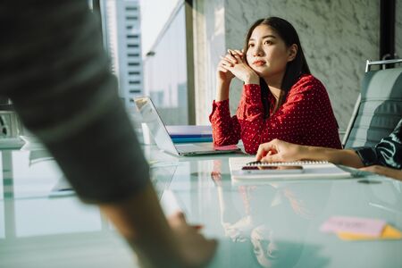 Beautiful young asian thai businesswoman in red shirt listen to people in conference room.の写真素材