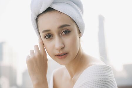 Close up of Young woman in white bathrobe wrap on head over city background.の写真素材