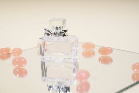 Perfume glass bottle on mirror plate surrounded with candy over white background.の写真素材