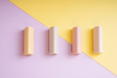 Commercial product - Group of pastel beige lipsticks on yellow and purple background.