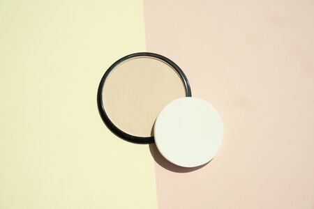 Face powder, cosmetic makeup, beauty product, face concealer, blush, jar container packaging, isolated on yellow and pink two tones background.の写真素材