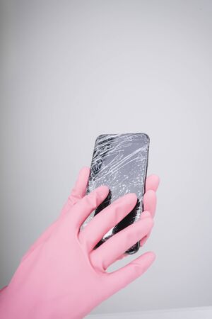 Covid-19 is everywhere. Hand of doctor in pink glove unwrap plastic cover from smartphone.の写真素材