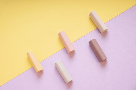 Commercial product - Group of pastel beige lipsticks on yellow and purple background.の写真素材