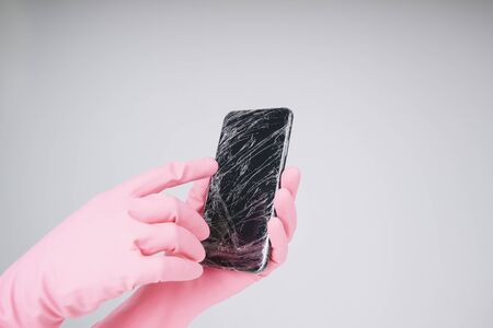 Covid-19 is everywhere. Hand of doctor in pink glove unwrap plastic cover from smartphone.の写真素材