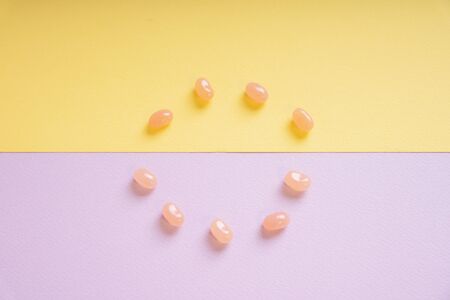 Sweet candy in circle form on purple and yellow background. Top view.の写真素材
