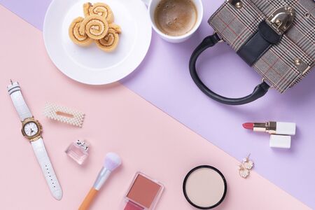 Top view - Cosmetic make up tools and dessert roll over pink and purple background. Woman girl...