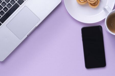 Top view - Working space with laptop, smartphone, dessert roll, and coffee cup.の写真素材