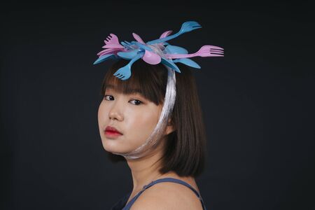 Young asian thai black short hair with utensil fork and spoon headband over dark background.の写真素材