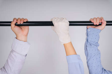 Closeup people hand wearing glove to prevent from covid-19, holding pole inside the train for safety...